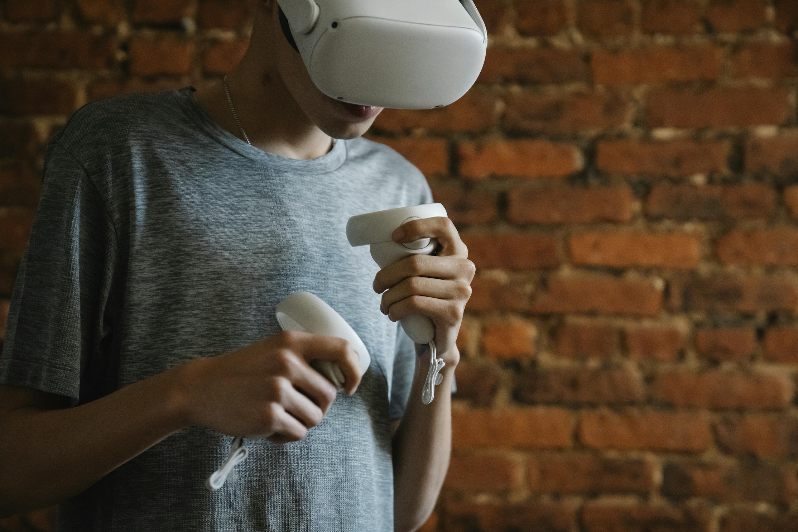 A young man engaging with virtual reality using a VR headset and controllers indoors.